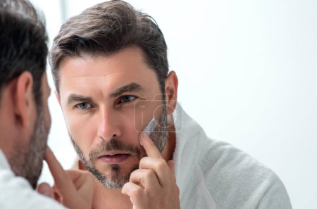 Man applying face cream. Beauty routine. Man with perfect skin. Anti-aging and wrinkle cream. Concept of male beauty. Close up face of man applying cream to skin. Skincare and cosmetics concept