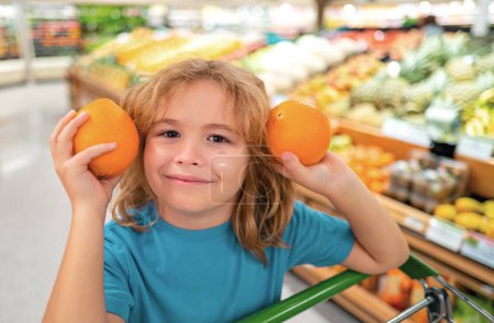 Foto de Niño con cesta llena de verduras y frutas. Un chico en una tienda de comida. Concepto de supermercado de compras y supermercados. Niño con cesta de la compra - Imagen libre de derechos