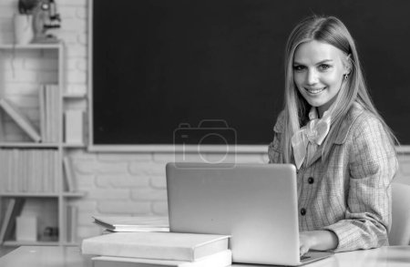 Photo for High school student sitting at table and writing on notebook, learning english or mathematics in class - Royalty Free Image