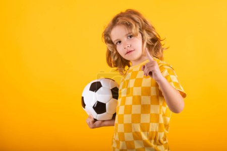 Photo for Child boy hold classic soccer ball isolated on yellow studio. Kid holding football ball in studio. Kid playing with ball. Sport, soccer hobby for kids. Little football player posing with soccer ball - Royalty Free Image