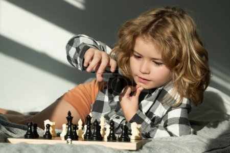 Photo for Kid play chess at home. Child thinking near chessboard. Learning and growing children, childgood. Kids early development - Royalty Free Image