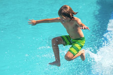 Téléchargez les photos : Il saute dans la piscine d'eau. Enfant excité nageant. Petit enfant jouant dans l'eau bleue de la piscine sur une station tropicale à la mer. Mignon garçon nager dans l'eau de la piscine - en image libre de droit