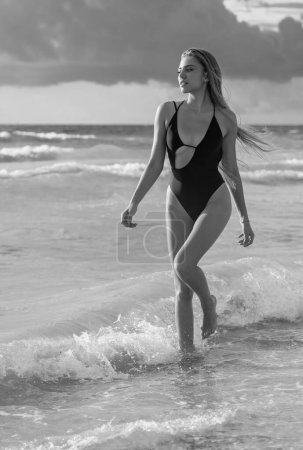Téléchargez les photos : Jeune femme en maillot de bain sur la plage. Loisirs en mer. Body maillot de bain sexy sur corps mince femme sur la plage tropicale paradisiaque. Belle fille de corps en voyage. Jeune fille à l'océan - en image libre de droit