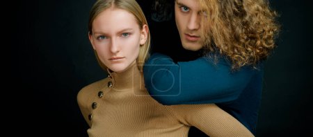 Photo for Couple of man with curly hair and blonde woman in hairdresser salon. Young couple hugging and embracing. Young fashion couple on black background in studio. Fashionable couple - Royalty Free Image