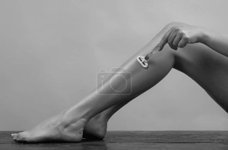 Foto de Mujer joven que usa crema calmante al afeitar las piernas con afeitadora después de la ducha. Quitando el pelo en las piernas sexys. Patas de mujer bastante delgadas con pelo. Hermosa mujer con piernas de afeitar utilizando espuma para afeitarse - Imagen libre de derechos