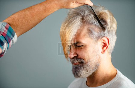 Photo for Hairdresser cutting male hair, closeup. Hairdresser does hair with black comb of handsome client in professional hairdressing salon. Barber concept - Royalty Free Image