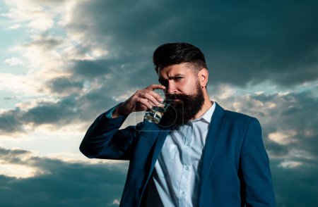 Trinkt Alkohol-Konzept, schöner bärtiger Mann trinkt teures Getränk