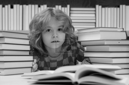 Téléchargez les photos : Un écolier lit un livre à la bibliothèque. Développement des enfants, apprendre à lire. Livres de lecture d'élèves dans une librairie - en image libre de droit