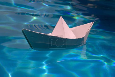 Photo for Paper boat on blue water background. Paper boat sailing on blue water surface. Concept of tourism, travel dreams vacation holiday, dreaming traveling, sailing adventure. Paper craft and origami - Royalty Free Image