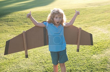 Foto de Viajero de niños con alas de mochila. Niño jugando piloto aviador y sueños al aire libre en el parque. Emocionado niño jugando al aire libre - Imagen libre de derechos
