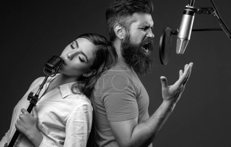 Téléchargez les photos : Couple chantant. Des chanteurs de karaoké. Homme et jeune femme chantant avec microphone de musique - en image libre de droit