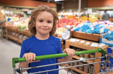 Photo for Kid with shopping cart at grocery store. Kid in a food store or a supermarket. Little kid going shopping. Healthy food for kids - Royalty Free Image