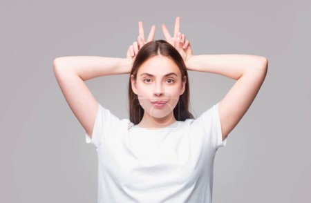 Photo for Young woman doing funny gesture with finger over head as bull horns. Crazy funny sexy girl doing funny gesture with finger over head as bull horns. Emotions on face - Royalty Free Image