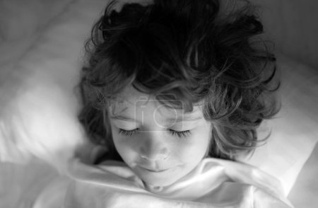 Téléchargez les photos : Les enfants adorables dorment. Enfant sur lit de couchage, heureux coucher dans la chambre blanche - en image libre de droit