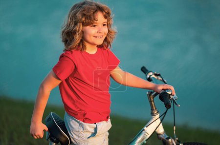 Happy kid boy riding bike in summer park. Bike dream. Dreamy kids face. Daydreamer child portrait close up. Dreams and imagination