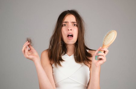 Photo for Hair loss. Woman is upset of hair loss. Portrait of sad girl with problem hair, isolated. Worried girl holding long damaged unhealthy hair in hand - Royalty Free Image