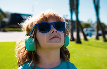 Photo for Sweet song. Kid listening to music. Summer boy in headphones. Child in earphones outdoor. Sunny portrait - Royalty Free Image