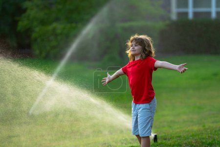 Photo for Cute little kid watering grass in the garden at summer day. Child play in summer backyard. Cute little boy is laughing and having fun running under water spraying sprinkler irrigation. Watering grass - Royalty Free Image