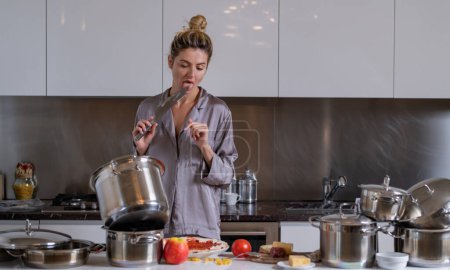 Photo for Sexy kitchen. Young woman cooking breakfast. Sexy slim woman at home in morning. Beautiful sensual female housewife in sexy pajama in kitchen cooking breakfast - Royalty Free Image