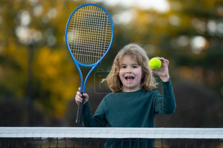 Foto de El Tenis. Niño con raqueta de tenis y pelota de tenis jugando en la cancha de tenis - Imagen libre de derechos