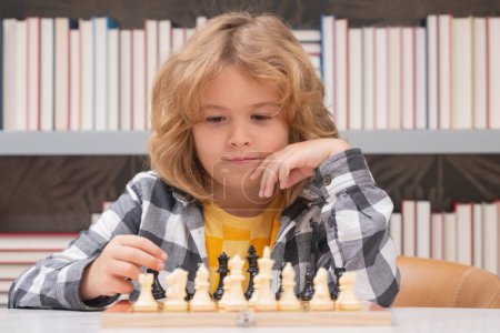 Téléchargez les photos : L'enfant pense au jeu d'échecs. Étudiant intelligent, intelligent et intelligent. Jeux pour le concept intelligence cérébrale - en image libre de droit