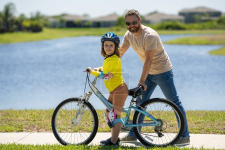 Photo for Father and son in a helmet riding bike. Little cute adorable caucasian boy in safety helmet riding bike with father. Family outdoors summer activities. Fathers day. Childhood and fatherhood - Royalty Free Image