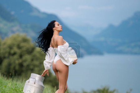 Foto de Chica del campo alpino con leche. Chica Sexy Vaca. Mujer sensual con leche al aire libre. Sensual mujer sostener la leche cerca de los Alpes suizos. Chica con una botella de leche fresca en el pueblo - Imagen libre de derechos