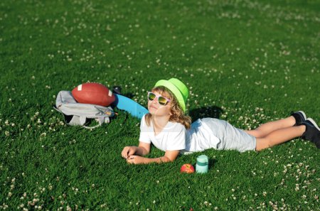 Photo for Happy kid boy enjoying on grass field and dreaming. Summer holiday. Carefree kid boy having fun on spring day at the park - Royalty Free Image