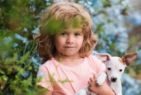 Foto de Retrato de un niño lindo jugando con su perro cachorro en el parque - Imagen libre de derechos