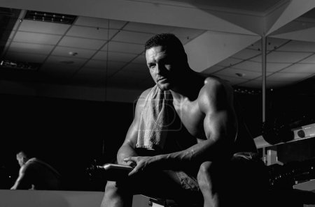 Foto de Deportista sin camisa descansando después de entrenar en el gimnasio. Hombre musculoso fuerte en el gimnasio crossfit. Concepto de estilo de vida de entrenamiento - Imagen libre de derechos