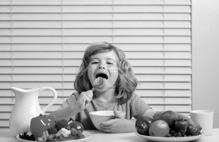 Foto de Hambre, concepto del apetito. Niño pequeño lame cuchara desayunando sano. Nutrición y desarrollo infantil. Comer verduras por niño las hace más saludables. - Imagen libre de derechos