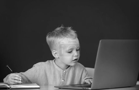 Photo for Cute little child using laptop computer, kid boy studying through online e-learning. Little funny system administrator. Funny blonde pupil on blackboard - Royalty Free Image