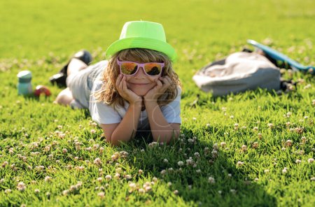 Photo for Cute child boy enjoy relax on lawn. Kid boy relax at park outdoor. Summer weekend. Summertime vacation - Royalty Free Image