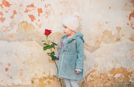 Photo for Happy childhood. retro fashion. happy birthday. wedding. little girl in vintage coat. Beauty. love present. childrens day. valentines day. romantic date - small kid with red rose. - Royalty Free Image