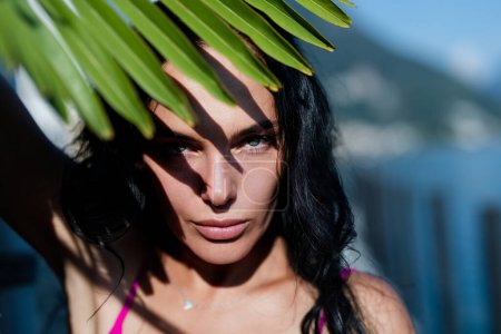 Photo for Pretty woman with leaves tropics on face. Beautiful girl in palm leaves. Beauty Portrait. Natural summer cosmetics. Summer sexy woman outdoor portrait. Shadows on woman face from tropical leaves - Royalty Free Image