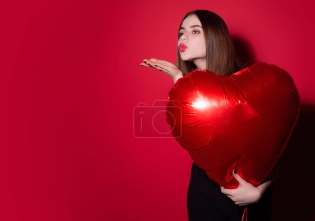 Foto de Mujer enamorada de corazón. Hermosa joven sosteniendo globos rojos del corazón, día de San Valentín. Una cita romántica. Mujer celebrando el Día de San Valentín. Retrato mujer bonita con forma de corazón de globo - Imagen libre de derechos