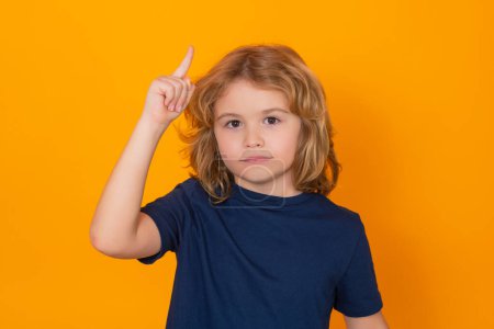 Photo for Kid pointing up finger on yellow background. Shocked kid pointing to copyspace, showing promo offers, points up - Royalty Free Image