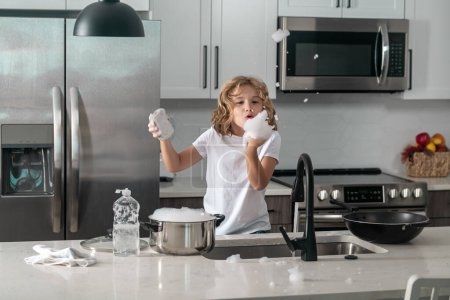 Photo for Home chores. Kid in kitchen cleaning plates. Cute boy washing dishes in domestic kitchen. Little housekeeper. Child washing and wiping dishes in kitchen - Royalty Free Image