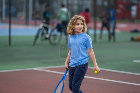 Téléchargez les photos : Enfant mignon jouant au tennis sur le court - en image libre de droit
