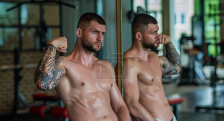 Photo for Strong young man exercising workout in gym. Sporty male workout in sports club. Young man has fitness workout. Male athlete does exercise, sport and training. People sport and healthy lifestyle - Royalty Free Image