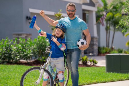 Photo for Kids insurance. Fathers day. Sporty family. Excited father and son with winning gesture. Father support child. Fathers love. Sporty kids. Cute boy with dad cycling in summer park outdoor - Royalty Free Image
