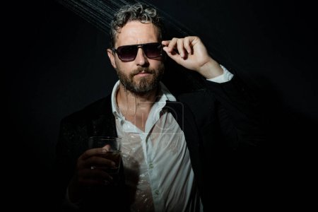 Photo for Night lifestyle. Sexy man in suit in bathroom after night party. Man drinking a whiskey after party in night club. Alcohol and drugs concept. Tired stressed business man under shower in bath. Night - Royalty Free Image