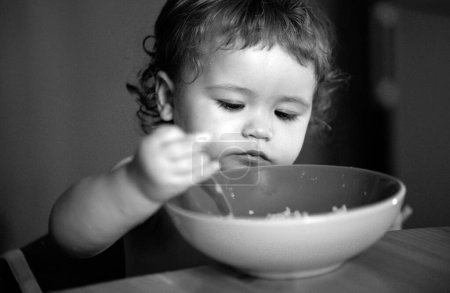 Téléchargez les photos : Bébé heureux se mangeant avec une cuillère. Concept de nutrition infantile - en image libre de droit