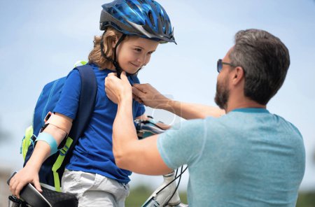 Photo for Insurance child. Father teaching son cycling on bike. Father learn little son to ride a bicycle. Father support and helping son. Fathers day concept. Father helping his son to wear a cycling helmet - Royalty Free Image
