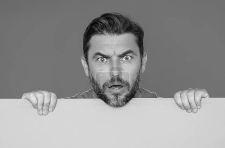 Photo for Angry man face with empty board on studio background. Anger guy showing blank signboard with copyspace. Idea and offer. Your advertisement. Blank advertising board with empty space for text, mockup - Royalty Free Image