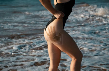 Foto de Closeup butt. Summer sunbathed sandy woman buttocks on sea of tropical beach background. Travel vacation wallpaper. Beautiful young girl in bikini with sand relax in sea paradise tropical Maldives - Imagen libre de derechos