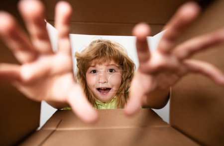 Child looking inside cardboard box, bottom view. Delivering your purchase. Kids celebrate birthday. Birthday gift. Child with open box take by hand gift