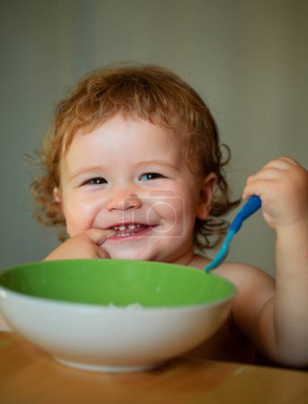 Téléchargez les photos : Bébé souriant mangeant des aliments. Lancement de manger enfant - en image libre de droit