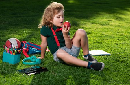 Photo for Kid sitting outdoor in garden eating apple. Lttle child outdoor school, education, on line distance learning - Royalty Free Image