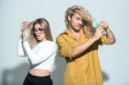 Two people man and woman with damaged hair. Haircare problem. Couple with hair loss problem. Damaged bad hair. Girl and guy with a hairbrush loosing hair. Hairs are tangled, frizzy and messy